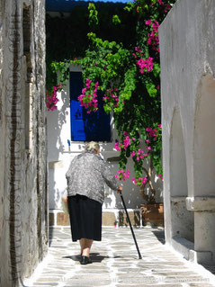 Grèce,vieille femme,canne,ruelle,arcades,murs blancs,arbres,volets bleus