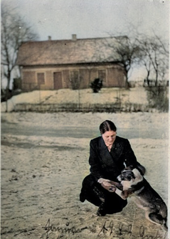 Margarete Albrecht vor dem Elternhaus Nr. 14. Im Hintergrund ist die unbefestigte Straße, rechts nach Labehnen, links nach Porschkeim zu sehen. Margarete dürfte sich also auf dem Nachbargrundstück Alterssitz Haus Schott befinden