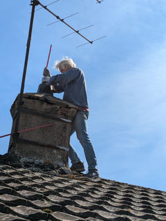 Mann beim Kehren des Kamins des Hauses in Plottes