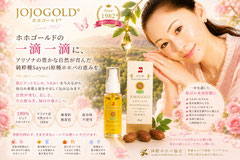 ホホゴールド®のPR画像。アリゾナ州原産の純粋種Sayuri原種ホホバオイルを使用したホホゴールド®30mlボトルと化粧箱を中央に配置。優しい笑顔の女性モデルとホホバの実、花々を背景に、肌・髪・頭皮・爪先まで全身に使える天然保湿オイルとして紹介している。1982年から続くロングセラー商品で、四季を通じたスキンケア・ヘアケアに活用できることを表現したイメージ。