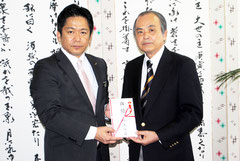 国債1億円の目録を中山市長に手渡す桃原さん(右)=20日午後、市役所