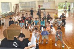 手作りの紙芝居を3人掛かりで操作。児童は食い入るように見つめていた=大本小学校、真栄里。