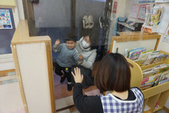 保育園から帰る子どもとお母さんとそれを見送る保育士