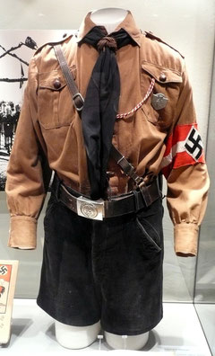 Hitlerjungenuniform aus den 1930er Jahren. Bestehend aus Braunhemd mit Effekten, kurzer Kordhose, Lederkoppel mit Schloss, Schulterriemen, Halstuch und Messer; Ersteller: WerWil, Lizenz:  Creative Com