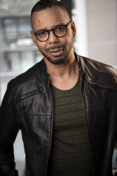 Das Bild zeigt David Santos Donaldson mit Lederjacke und Brille.
