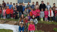 Les élèves de cours moyen et de maternelle à côté de leur jardin