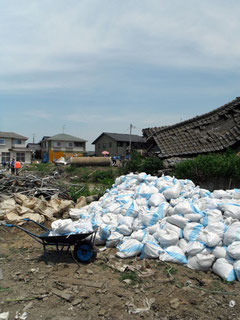 Bags, wheelbarrow, and flattened house