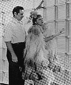 Between the scenes of Columbia´s THEODORA GOES WILD, Irene Dunne examines a new decorating invention, glass bricks, with director Richard Boleslawski