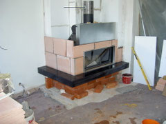 Anbringen der großformatigen Sitzbankkeramik, Aufmauern der Strahlungsflächen aus Schamotte, Verbinden des Abgasstutzens mit dem Schornstein