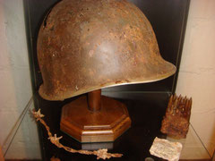 US M1 combat helmet together with a 30-06 caliber clip for the M1 Garand all found in Ste. Marie-du-Mont as well as a fragment for coffee ration which came from Utah Beach