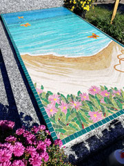 décoration en mosaique pour une pierre tombale représentant un paysage de plage en Sardaigne avec des fleurs roses au cimetière de Plailly