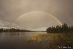 Doppelter Regenbogen spiegelt sich im See