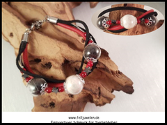 AB 20: Glasperlen (14mm) mit Haaren gefüllt, rote Jadeperlen und Hämatitsternchen. Schwarzes Velourlederband und rotes Nappaleder sind mit angebracht. Verschluss aus Edelstahl.Preis: 55 Euro.