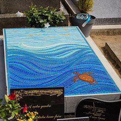 Vue d'ensemble d'un monument funéraire au cimetière de L'Isle-Adam, dont la dalle est entièrement recouverte d'une mosaïque bleue azur représentant les fonds marins et une tortue marine.
