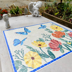 Mosaïque funéraire pour enfant représentant des papillons bleus et des fleurs colorées sur une tombe.