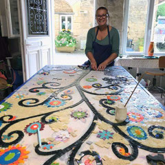 Artiste mosaïste dans son atelier en plein travail de création minutieuse d'une œuvre funéraire personnalisée pour une sépulture.