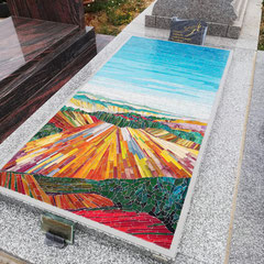  Mosaïque funéraire colorée interprétant une peinture paysagère, posée sur une dalle en granit Tarn gris dans un cimetière