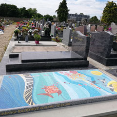 Monument funéraire coloré avec une décoration pour tombale originale en mosaïque représentant un piano et des poissons.