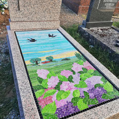 Monument funéraire en granit rose orné d'une mosaïque paysagère avec hortensias et hirondelles en plein vol.
