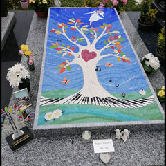 Vue d'ensemble d'une dalle funéraire en granittarn gris   entièrement recouverte d'une mosaïque lumineuse représentant un arbre de vie , un ange veille , quelques notes de musiques