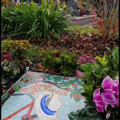 Mosaïque d'art funéraire posée sur une cavurne, ayant pour dessin un vélo, un chapeau et des fleurs, installée au cimetière de Cesson-Sévigné