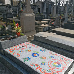 Vue en perspective d'une tombe recouverte d'une mosaïque colorée au milieu d'autres sépultures au  cimetière du montparnasse 