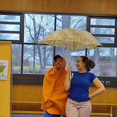Die Schauspieler stehen unter einem Regenschirm