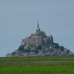 Von weit her sieht man den Mont St. Michel aus dem Meer aufragen.