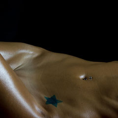 Nudo artistico di Ilaria, pelle bronzea esaltata da olio e luce radente, fotografia scultorea di Alessandro Tintori.