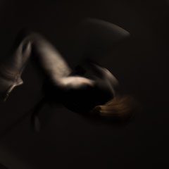 Performer Chiara Paradisi in posa su cerchio aereo (aerial hoop) con body painting nero su fondo nero - Fotografia di Alessandro Tintori