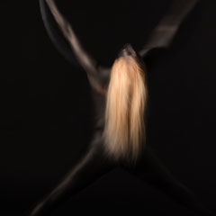 Performer Chiara Paradisi in posa su cerchio aereo (aerial hoop) con body painting nero su fondo nero - Fotografia di Alessandro Tintori