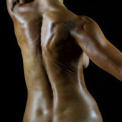 Nudo artistico di Ilaria, pelle bronzea esaltata da olio e luce radente, fotografia scultorea di Alessandro Tintori.