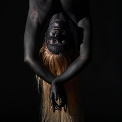 Performer Chiara Paradisi in posa su cerchio aereo (aerial hoop) con body painting nero su fondo nero - Fotografia di Alessandro Tintori