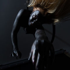Performer Chiara Paradisi in posa su cerchio aereo (aerial hoop) con body painting nero su fondo nero - Fotografia di Alessandro Tintori