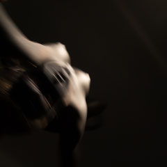 Performer Chiara Paradisi in posa su cerchio aereo (aerial hoop) con body painting nero su fondo nero - Fotografia di Alessandro Tintori