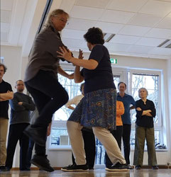 Szene aus einem Taiji-Workshop. Die Lehrerin zeigt der Gruppe eine sogenannte Anwendung aus den Partnerübungen