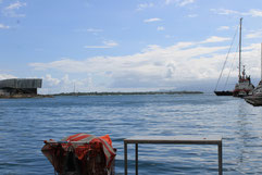 Le plan d'eau de la Darse : l’échoppe d'un écailleur de poisson, le Mémorial ACTe, l'îlet cochon, les montagnes de la Basse-Terre et les ports de Jarry et Pointe à Pitre (Photo WKTL-AGENCY, Février 2015, Pointe à Pitre, Guadeloupe) 