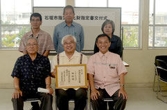 文化財指定の喜びを分かち合う新垣委員(後列右)や宮良信世館長(前列中央)ら関係者=石垣市教育委員会