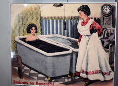 Historic painted postcard from Kemeri Sanatorium of a woman in a mud bath with a maid in a long white skirt standing beside the bath