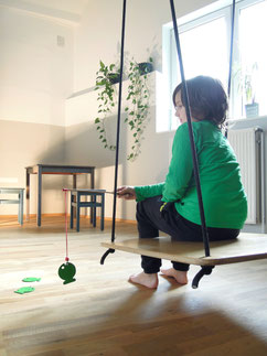 Kind in Praxis auf Holzschaukel