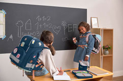 Mädchen im Klassenzimmer mit Schulranzen von LÄSSIG