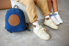 Kinder mit Tennissocken und Kinderrucksack Smilevon LÄSSIG auf Sitzbank 
