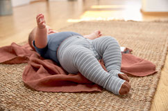 Baby mit Strumpfhose auf Krabbeldecke