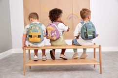 3 Kinder mit Rucksäcken von LÄSSIG sitzend auf einer Bank
