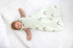 Baby im Ganzjahresschlafsack im Kinderbett