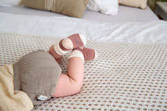 Baby mit Söckchen auf Krabbeldecke
