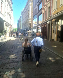 Girl in a wheelchair and her assistant going down a cobblestone street in Old Riga, Latvia