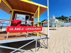 Red sign saying lifeguards in Latvian and Eng;ish on beach in Jurmala, Latvia.