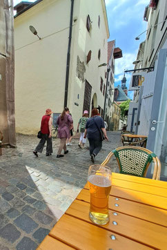 Glass of beer on wooden table in narrow street in Riga Old Town, Latvia