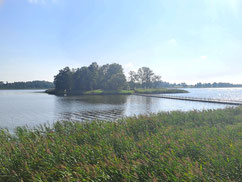 Island in lake near Viļaka, Latvia, with wooden footbridge connecting to shore